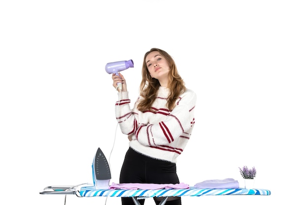 Front view young housewife holding hairdryer on white