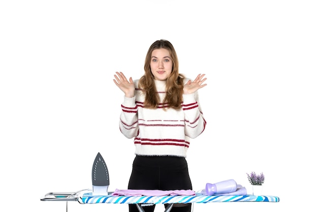 Front view young housewife behind ironing board on white