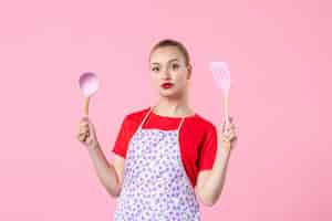 Free photo front view young housewife posing with cutlery on pink wall