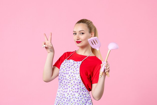 Front view young housewife with cutlery in her hands on pink wall