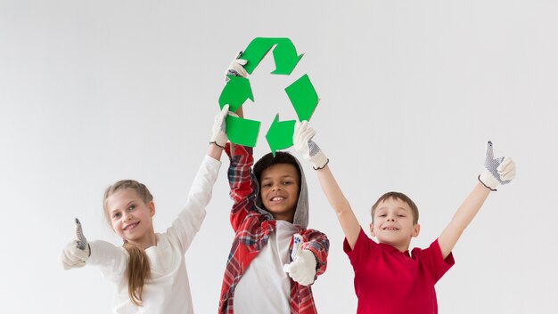 Front view young kids holding recycle sign