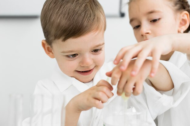 Front view of young kids scientists with test tubes