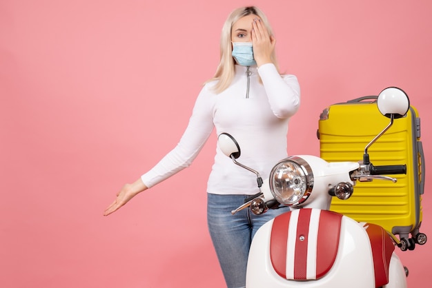 Front view young lady covering eye with hand standing near moped