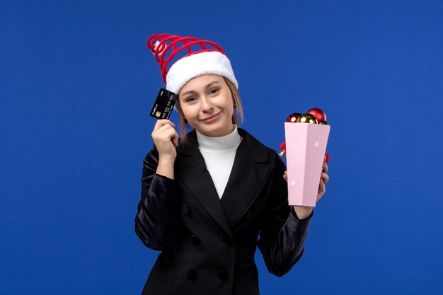 Front view young lady holding bank card on blue wall new year emotion holiday toy