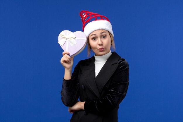 Front view young lady holding heart shaped present on blue wall new year holidays gifts