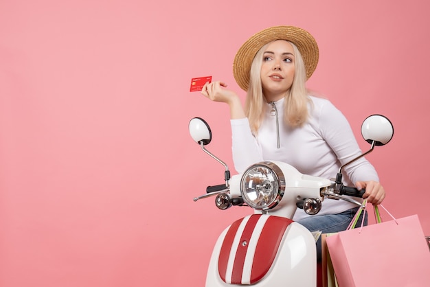 Front view young lady on moped holding card thinking about something