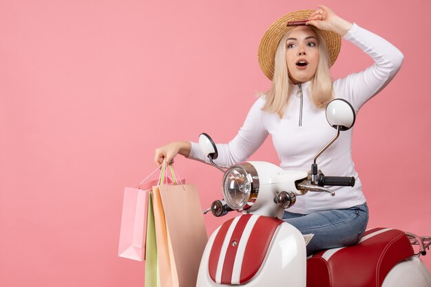 Front view young lady on moped holding shopping bags in a hurry