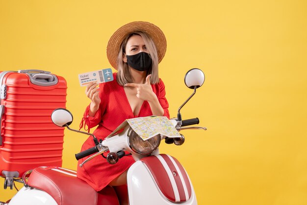 Front view young lady on moped with big suitcase holding ticket