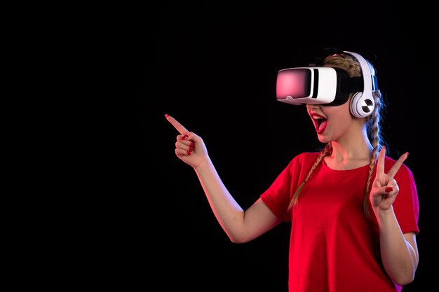 暗い壁にヘッドフォンで vr をしている若い女性の正面図