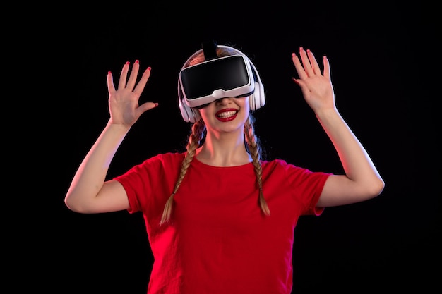 Front view of young lady playing vr in headphones on dark wall