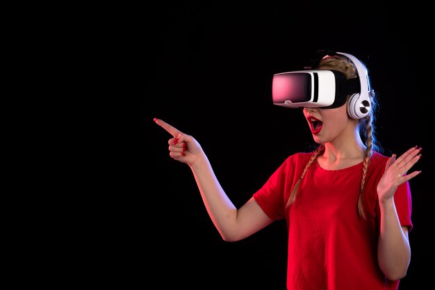 Front view of young lady playing vr in headphones on dark  