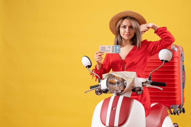 Front view young lady in red dress holding ticket showing arm muscle on moped