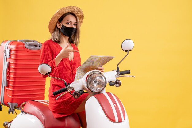 그녀의 손에지도에서 가리키는 오토바이에 빨간 드레스에 전면보기 젊은 아가씨