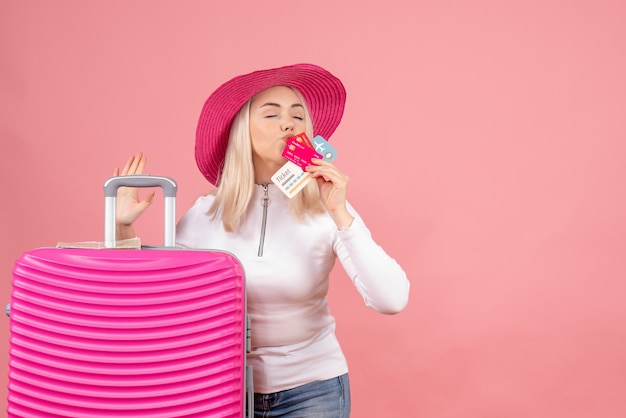 Free photo front view young lady standing near suitcase kissing cards and ticket