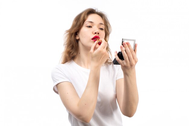 A front view young lady in white shirt and black trousers doing makeup on the white