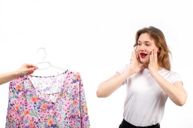 Una giovane signora di vista frontale in camicia bianca e pantaloni neri che ottengono la camicetta disegnata fiore sul bianco