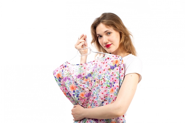 A front view young lady in white shirt and black trousers holding flower designed blouse shirt on the white