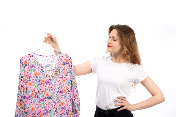 मुफ़्त फोटो a front view young lady in white shirt and black trousers holding flower designed blouse shirt on the white