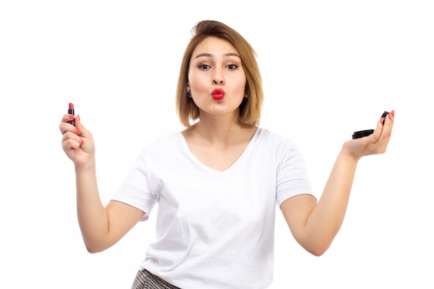 A front view young lady in white shirt and light modern trousers doing makeup on the white