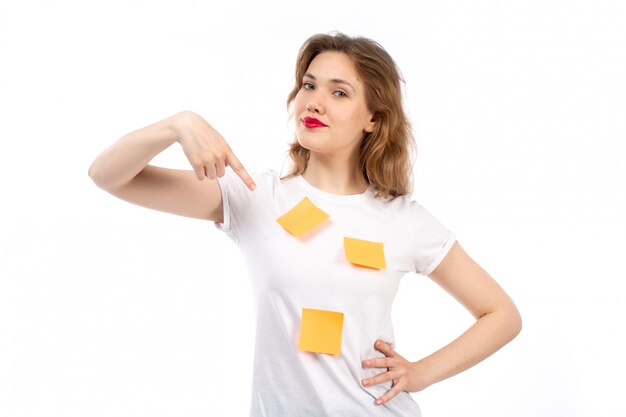 A front view young lady in white shirt with orange notes and black modern jeans posing smiling on the white