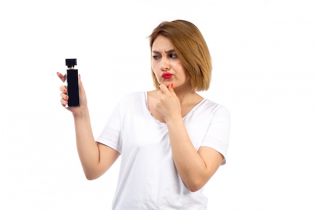 A front view young lady in white t-shirt holding black perfume tube not sure expression on the white