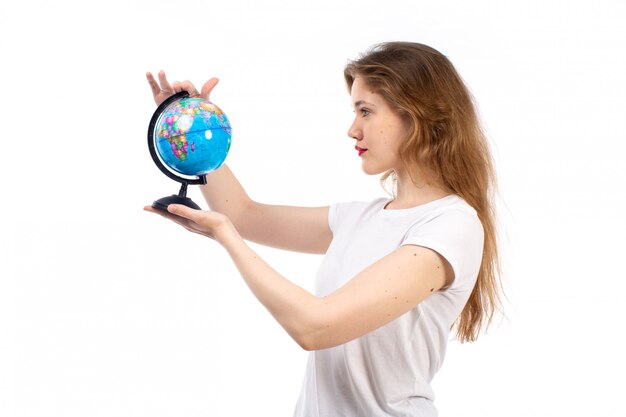 A front view young lady in white t-shirt holding little round globe on the white