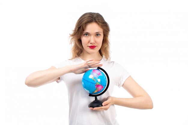 A front view young lady in white t-shirt holding little round globe on the white