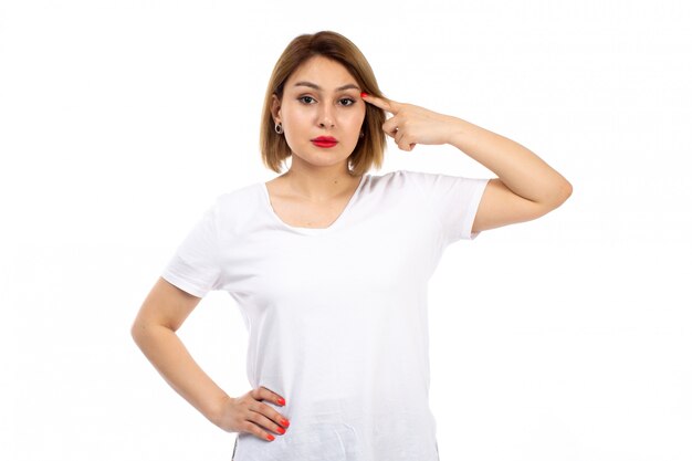 Вид спереди молодая дама в белой футболке позирует думать на белом