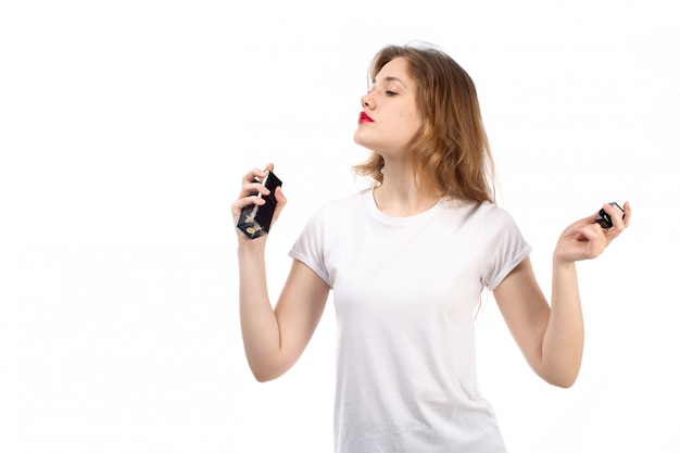 A front view young lady in white t-shirt using black perfume tube on the white