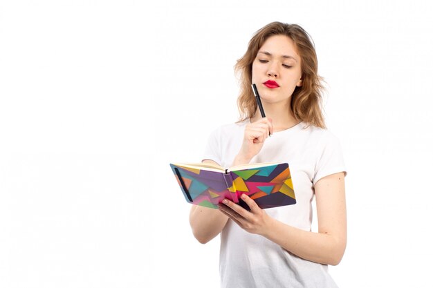 A front view young lady in white t-shirt writing down notes on the white