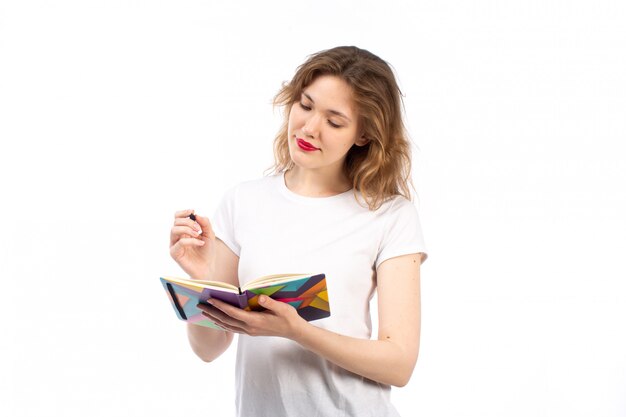 A front view young lady in white t-shirt writing down notes on the white