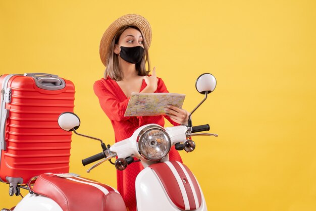 Front view young lady with black mask holding map near moped