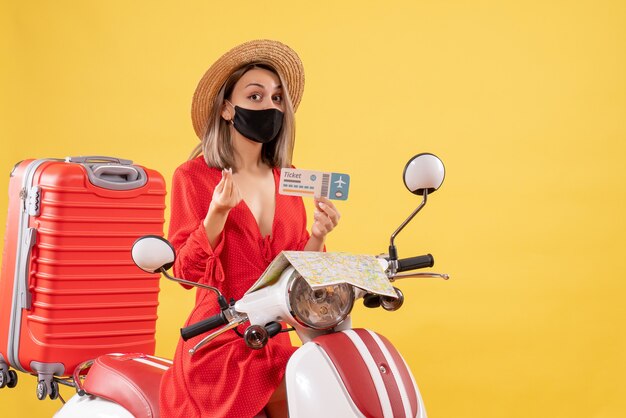 Front view young lady with black mask on moped holding ticket making money sign