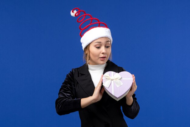 Front view young lady with heart shaped present on blue wall new year holiday gifts