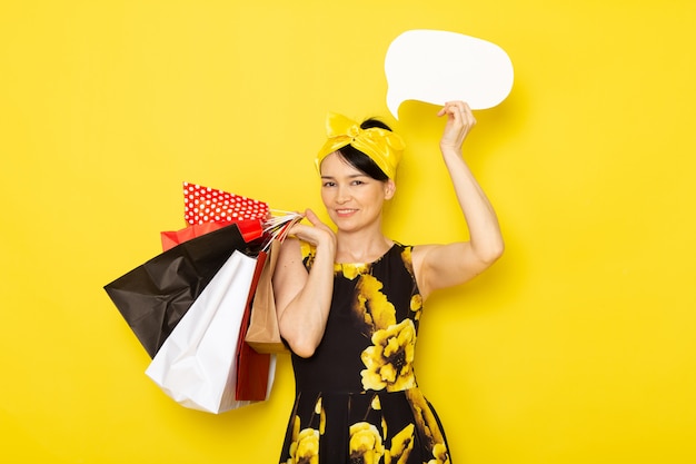노란색-검은 꽃의 전면보기 젊은 아가씨는 노란색에 쇼핑 패키지를 들고 머리에 노란색 붕대로 드레스를 설계