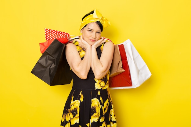 노란색-검은 꽃의 전면보기 젊은 아가씨는 노란색에 쇼핑 패키지를 들고 머리에 노란색 붕대로 드레스를 설계