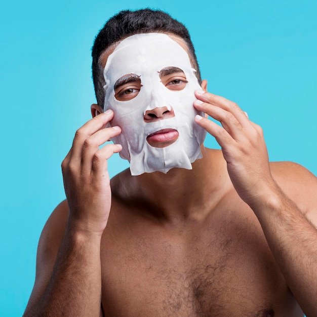 Front view young male applying a facial mask