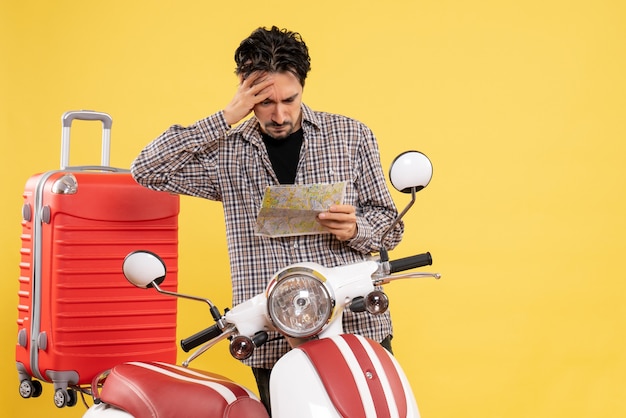 Front view young male around bike observing map on yellow background road vacation ride motorcycle voyage