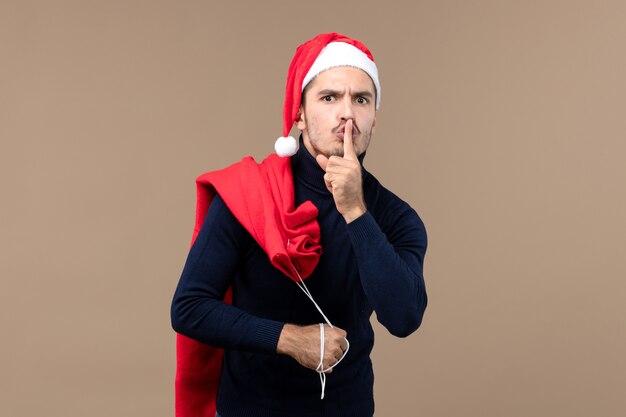 Front view young male asking to be quiet on a brown background christmas holiday santa