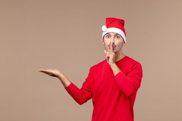 茶色の机のクリスマスの感情の休日に沈黙を保つように求める正面図若い男性
