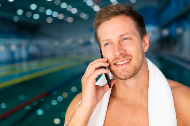 무료 사진 전화로 얘기하는 수영장에서 전면보기 젊은 남성