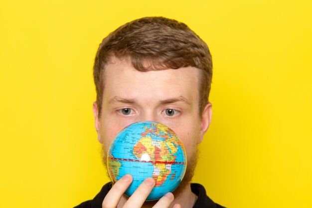 Front view of young male in black shirt holding little globe