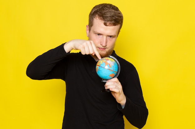 Free photo front view of young male in black shirt holding little globe