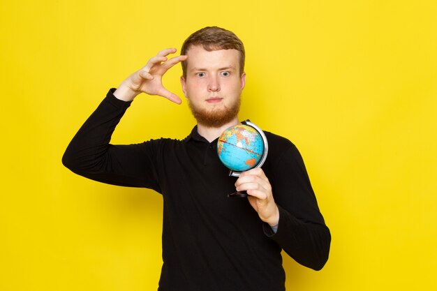 Front view of young male in black shirt holding little globe