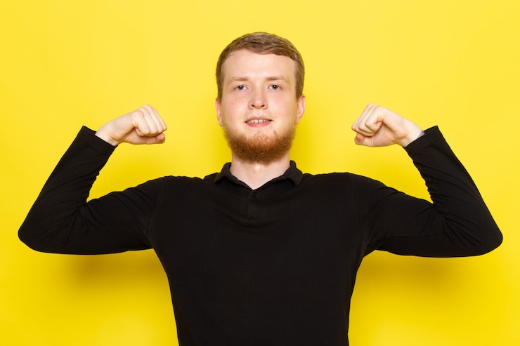 Free Photo front view of young male in black shirt posing and flexing on the yellow surface
