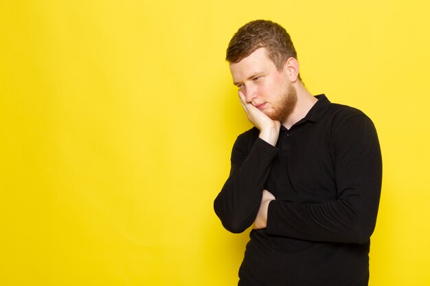 Front view of young male in black shirt posing and having a toothache