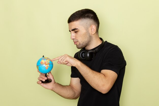 Front view young male in black t-shirt holding little globe on green