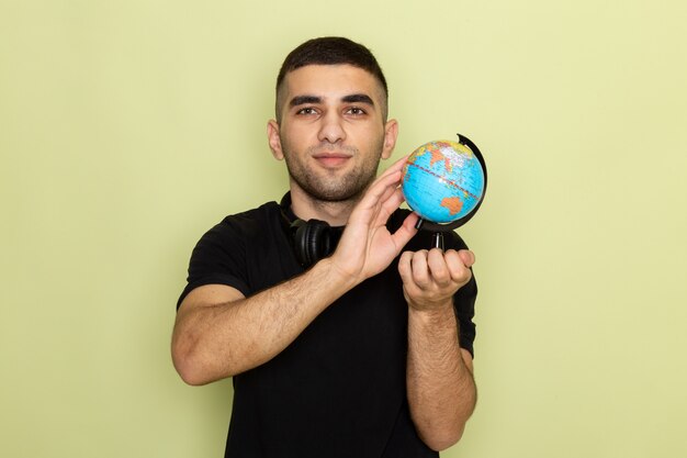 front view young male in black t-shirt holding little globe on green