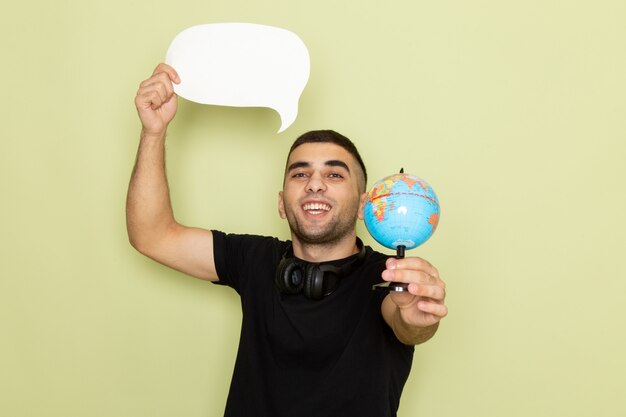 Front view young male in black t-shirt holding white sign and little globe on green