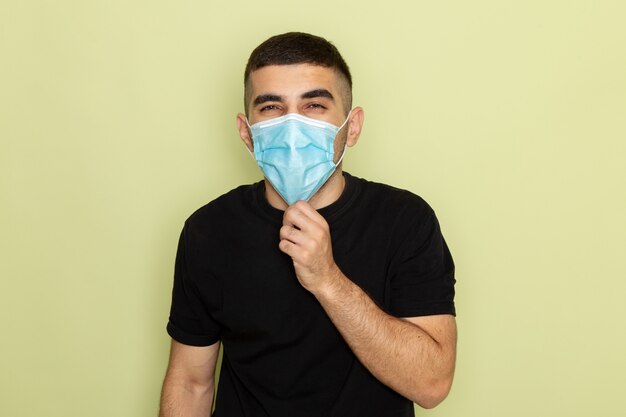 Front view young male in black t-shirt wearing sterile mask on green